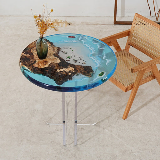 Modern artistic resin table showcasing a beach scene with waves and wood, complemented by a woven chair.