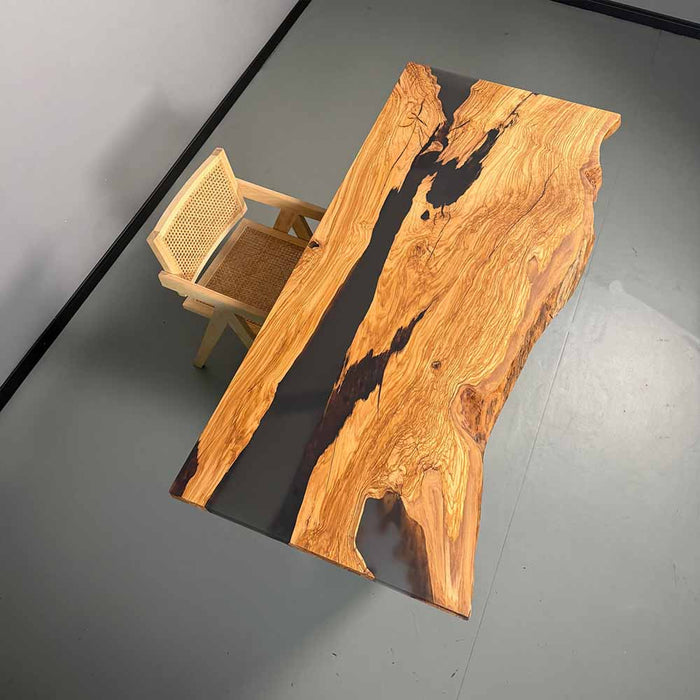 Wooden dining table with a natural finish and a chair on a gray floor.