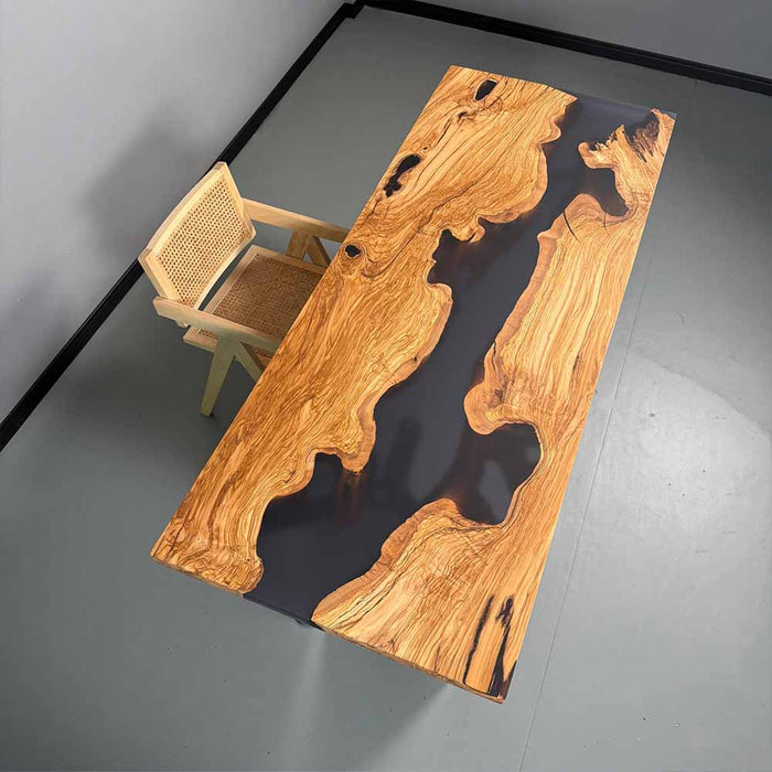 Wooden table with black resin inlay and a chair on a gray floor.