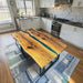 Modern custom olive wood epoxy dining table featuring a clear blue resin river.