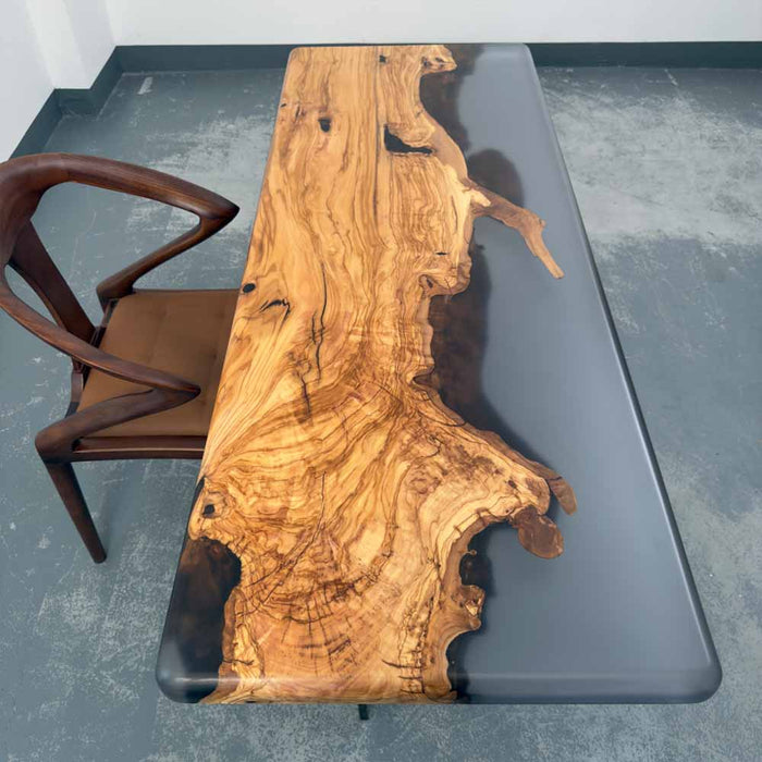 Wooden desk with a natural grain pattern next to a chair on a gray floor.