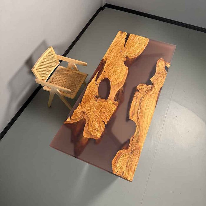 Wooden table with natural grain pattern and a woven chair on a gray floor.