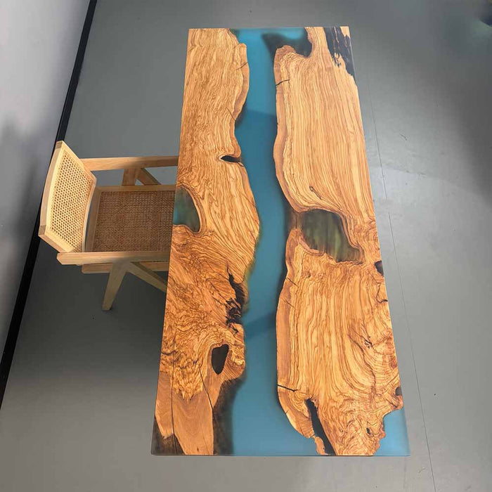 Wooden table with blue resin inlay and wicker chair in the background