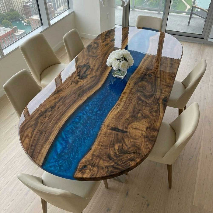 A luxury oval black walnut dining table with a deep blue swirl resin river in a bright high-rise apartment.