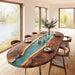 Dining room with a long wooden table featuring a blue resin inlay, surrounded by chairs.