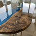 Large oval black walnut and blue resin table used as a modern executive conference table in an office setting.