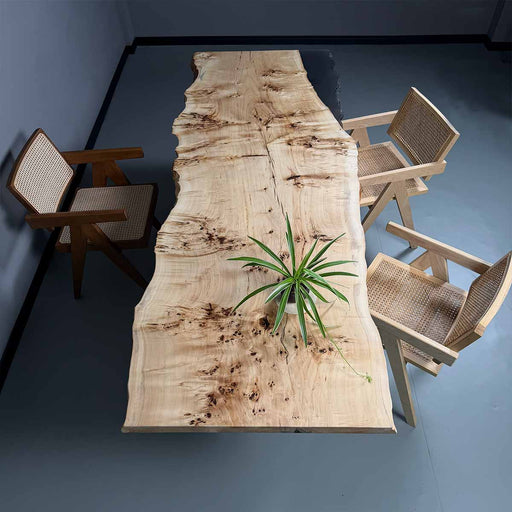 Wooden dining table with natural finish and four chairs in a room.