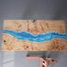 Close-up view of resin ocean wave detailing embedded in poplar wood table surface.