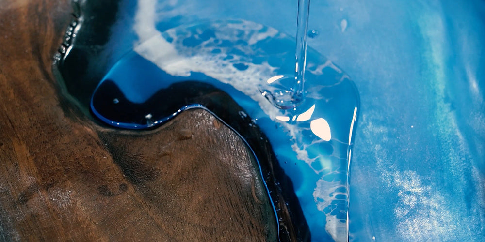 Pouring resin into wood mold to create epoxy river table design