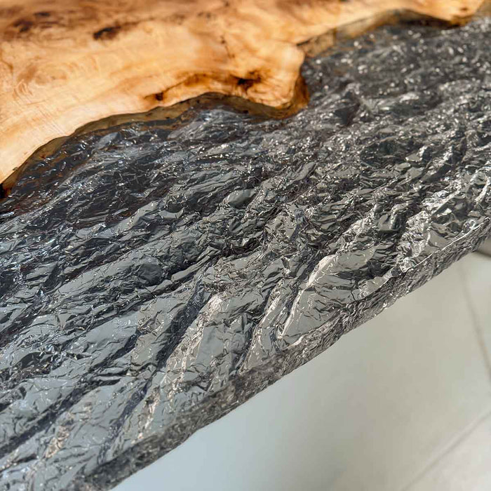 Close-up of a dark gray stone surface with a light wood edge.