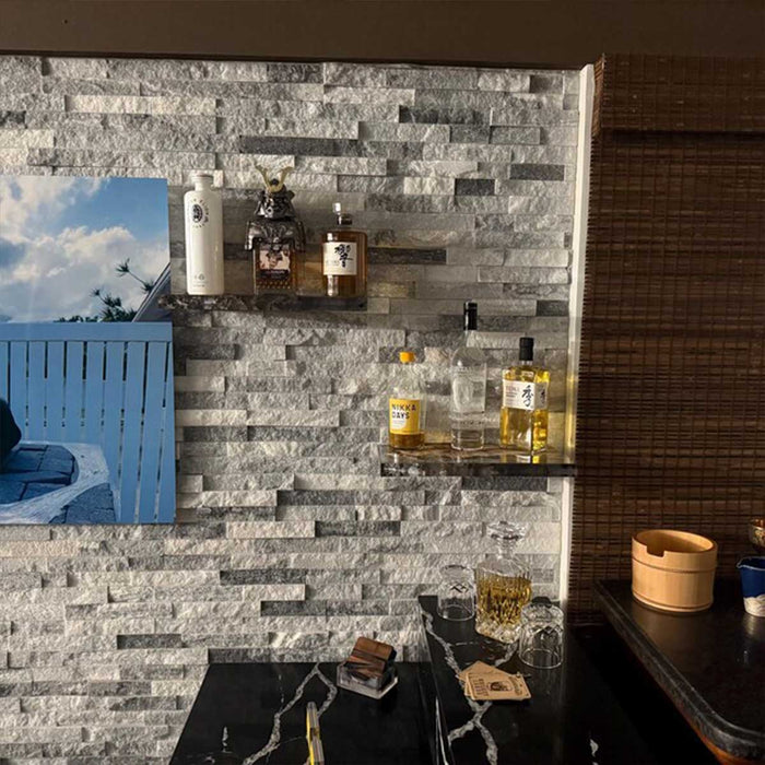 Shelves with bottles against a stone wall in a bar setting