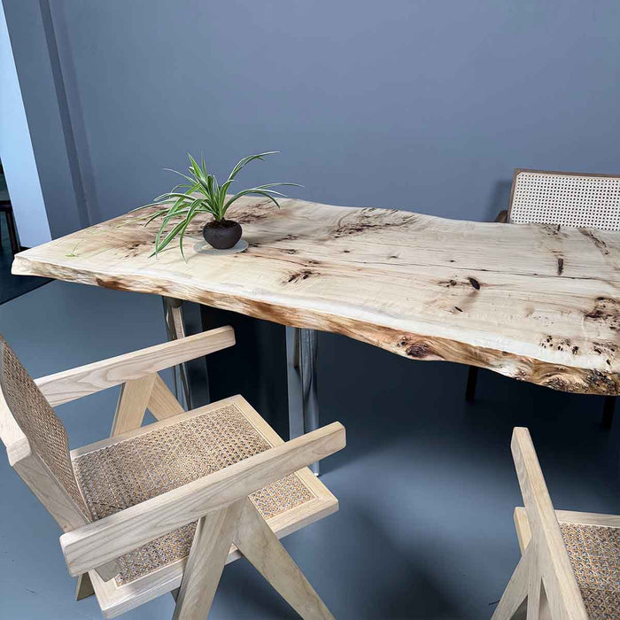 Wooden dining table with natural finish and chairs against a blue wall.