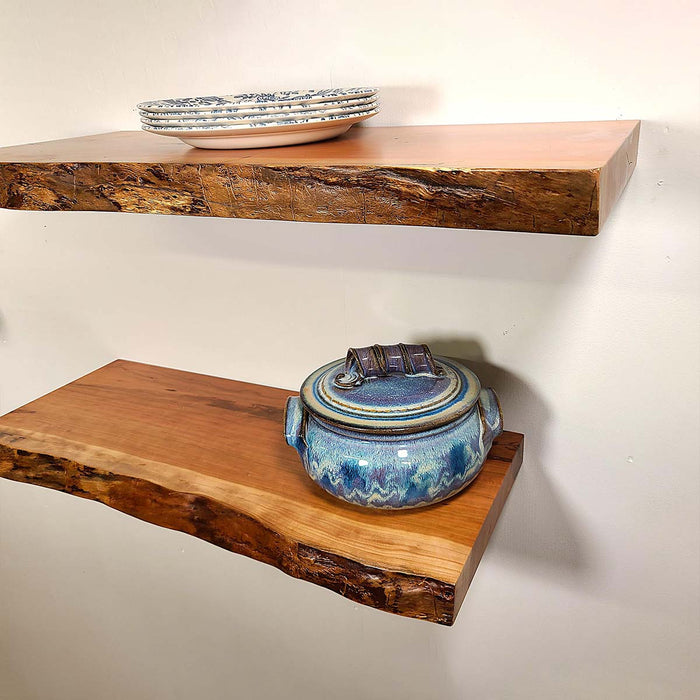 Two wooden shelves with ceramic pots on a plain background