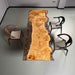 Wooden dining table with a burl pattern in a room with chairs.