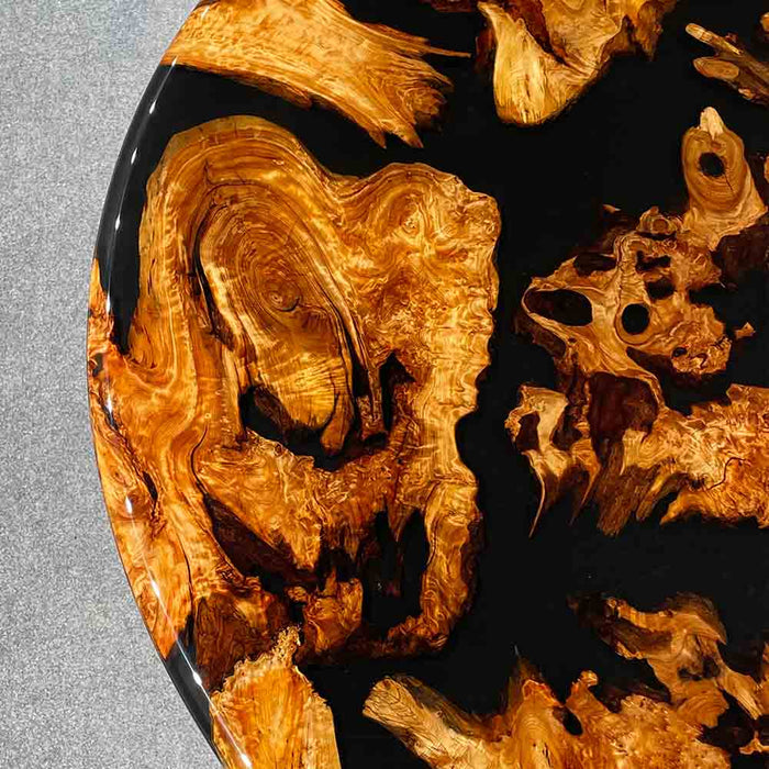 Close-up of a wooden surface with black resin, on a gray background