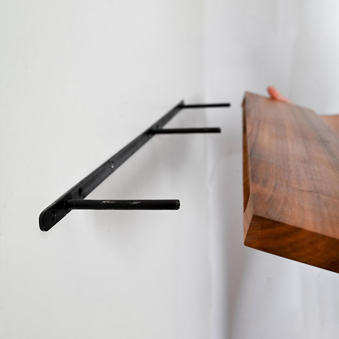 Wooden shelf with a black metal bracket against a white wall
