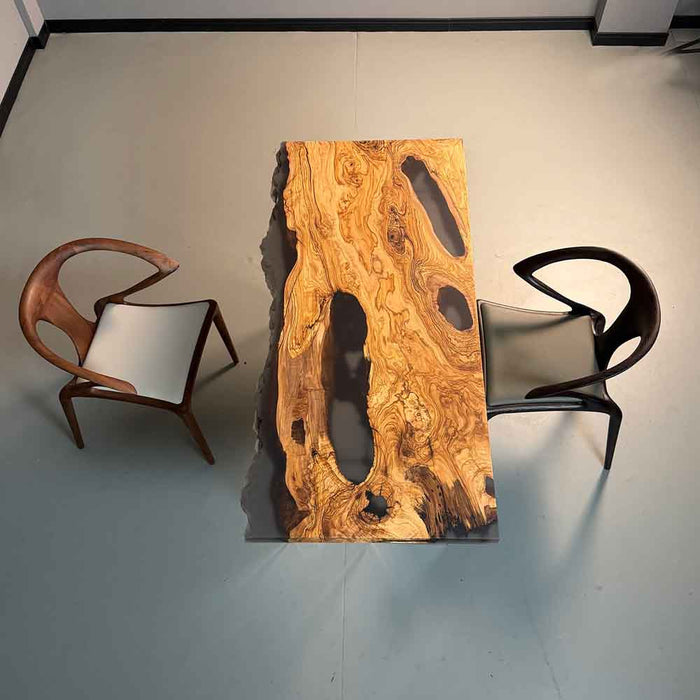 Wooden dining table with natural grain pattern and two chairs on a plain floor.