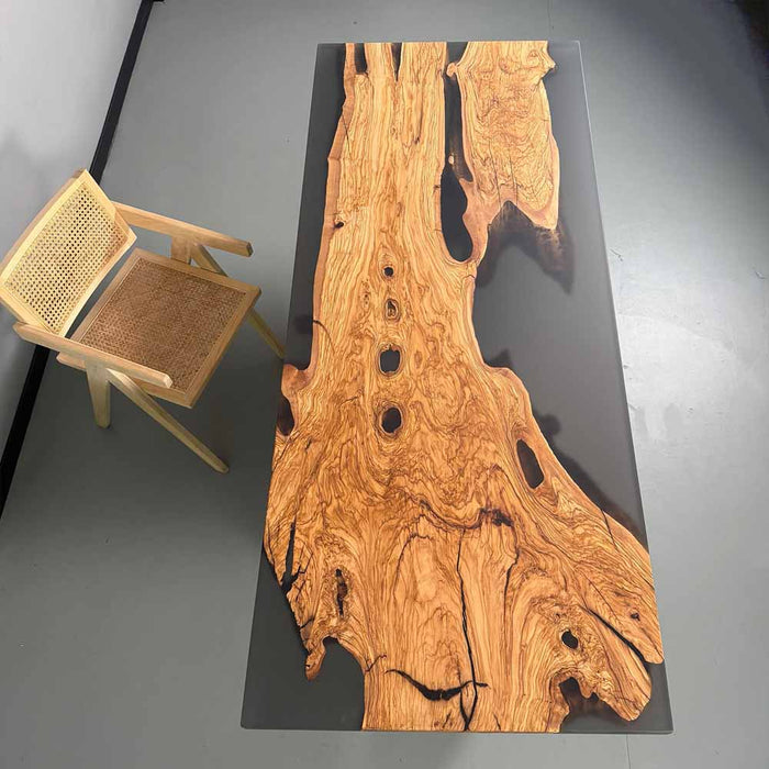 Wooden table with natural grain pattern next to a chair on a gray floor.