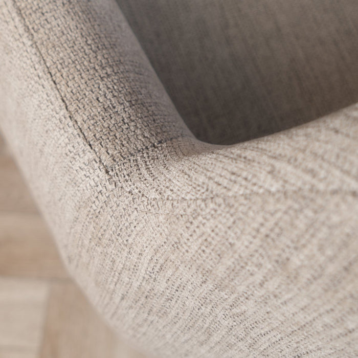 Close-up of a textured gray chair armrest on a wooden floor.