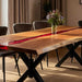 Wooden dining table with red inlay and black metal legs in a room setting.