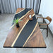 Wooden desk with black epoxy finish, plant, and decorative item in a room setting.