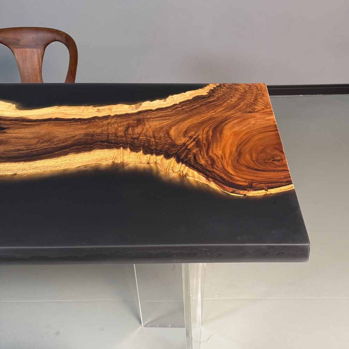 Dining table with black surface and wooden grain pattern, chair partially visible.