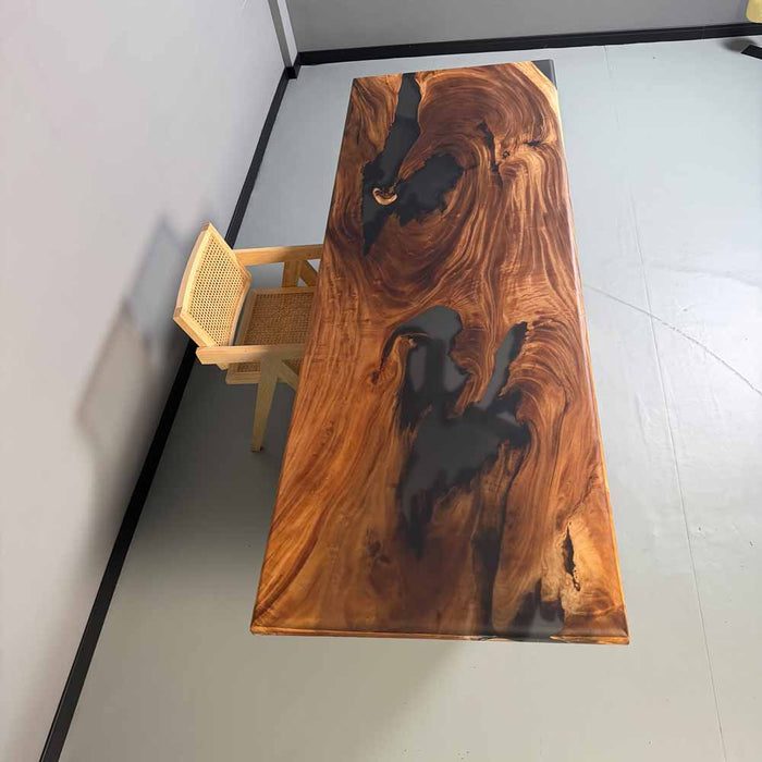 Wooden table with black resin inclusions in a minimalistic room.