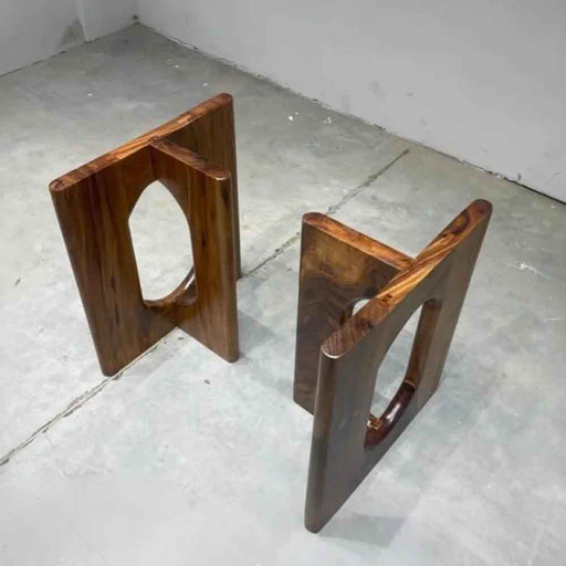 Two wooden stools on a concrete floor with a white wall background