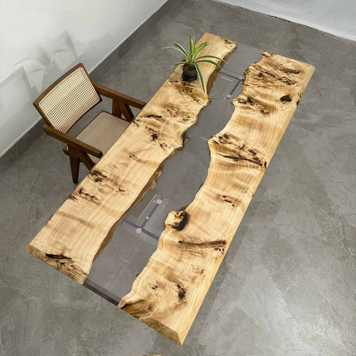 Wooden dining table with a natural, uneven surface in a room with a chair and plant.
