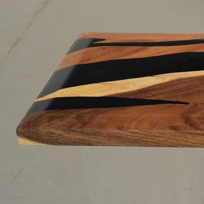 Wooden cutting board with black and gold stripes on a gray surface