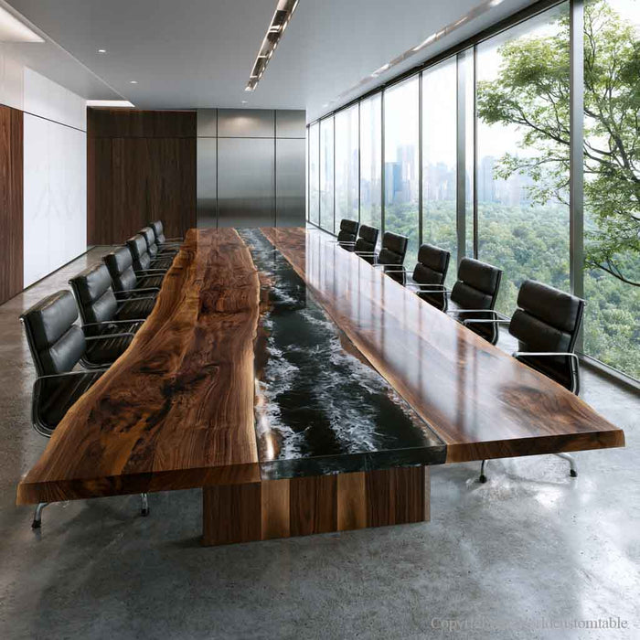 A modern conference room featuring a long live-edge wooden table with a glossy black resin river running down the center, surrounded by black office chairs and large floor-to-ceiling windows overlooking a green forest.