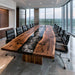 A modern living room or conference space featuring a large rectangular table with a live-edge natural wood top and a glossy black resin center channel. Multiple black office chairs with chrome bases are arranged around the table, which is set in a bright room with large floor-to-ceiling windows overlooking a city skyline.