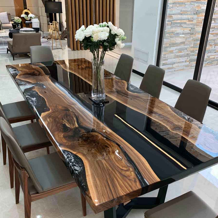 Luxury black walnut dining table featuring a deep black epoxy river with natural live edge wood in a modern dining room.