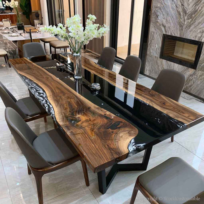 A modern live-edge wooden dining table with a glossy black center channel, surrounded by gray upholstered dining chairs in a contemporary dining room setting.