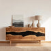Wooden sideboard with black resin accents in a room with a lamp and abstract painting.