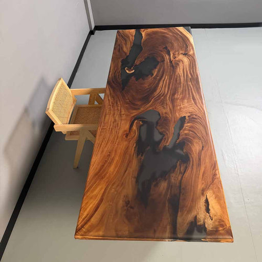 Wooden dining table with black resin inclusions in a minimalistic room.