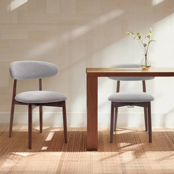Dining table with two chairs in a room with sunlight filtering through a window.