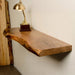 Wooden shelf with a gold lamp on a white wall