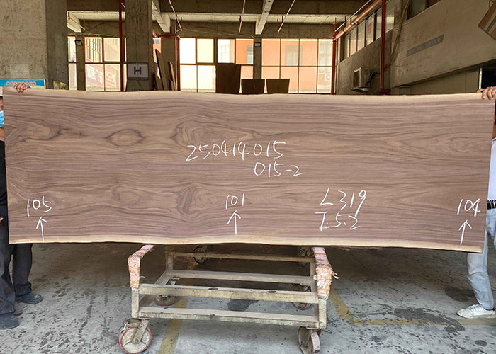 Large wooden panel with measurements being held by two people in an indoor setting.