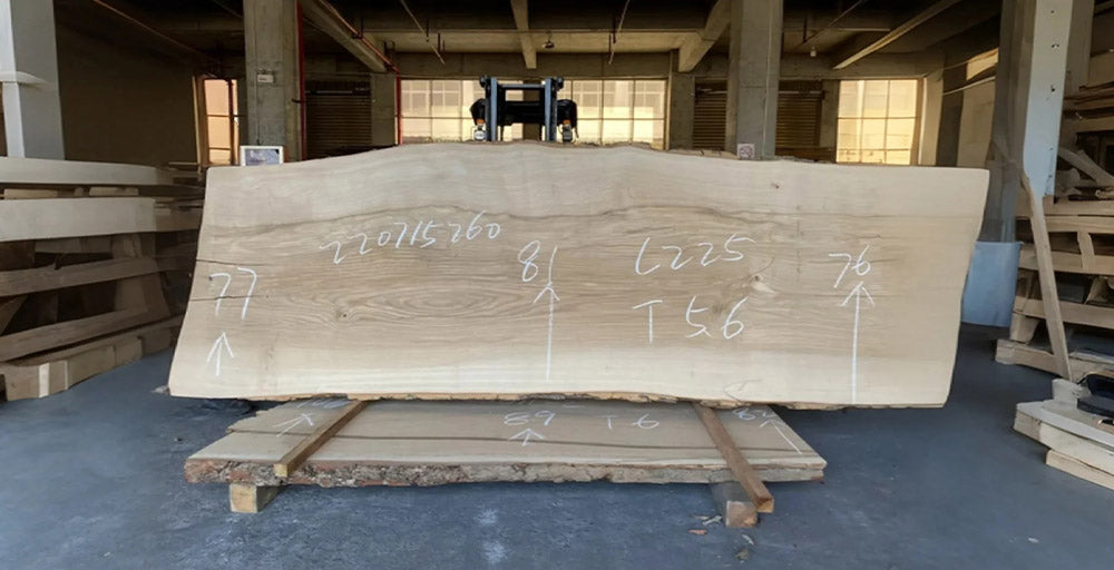 Large wooden slab with measurements on a pallet in an indoor setting
