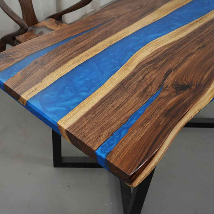 Wooden table with blue resin inlay on a gray floor.