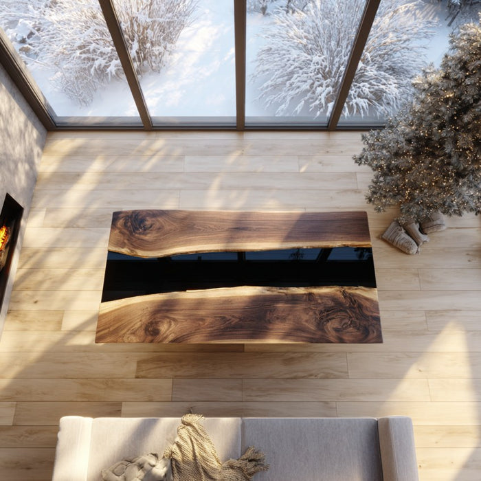 Wooden coffee table with black resin inlay in a room with large windows showing snow outside.