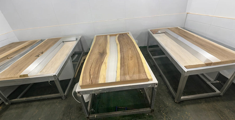 Three wooden tables with metal frames on a concrete floor.
