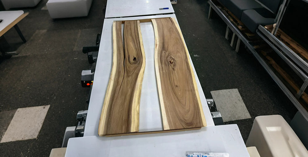 Wooden slab with white resin on a conveyor belt in an industrial setting