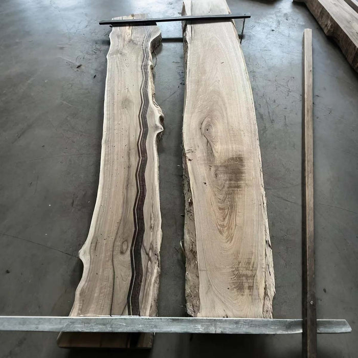 Two large wooden slabs with natural grain patterns on a concrete floor.